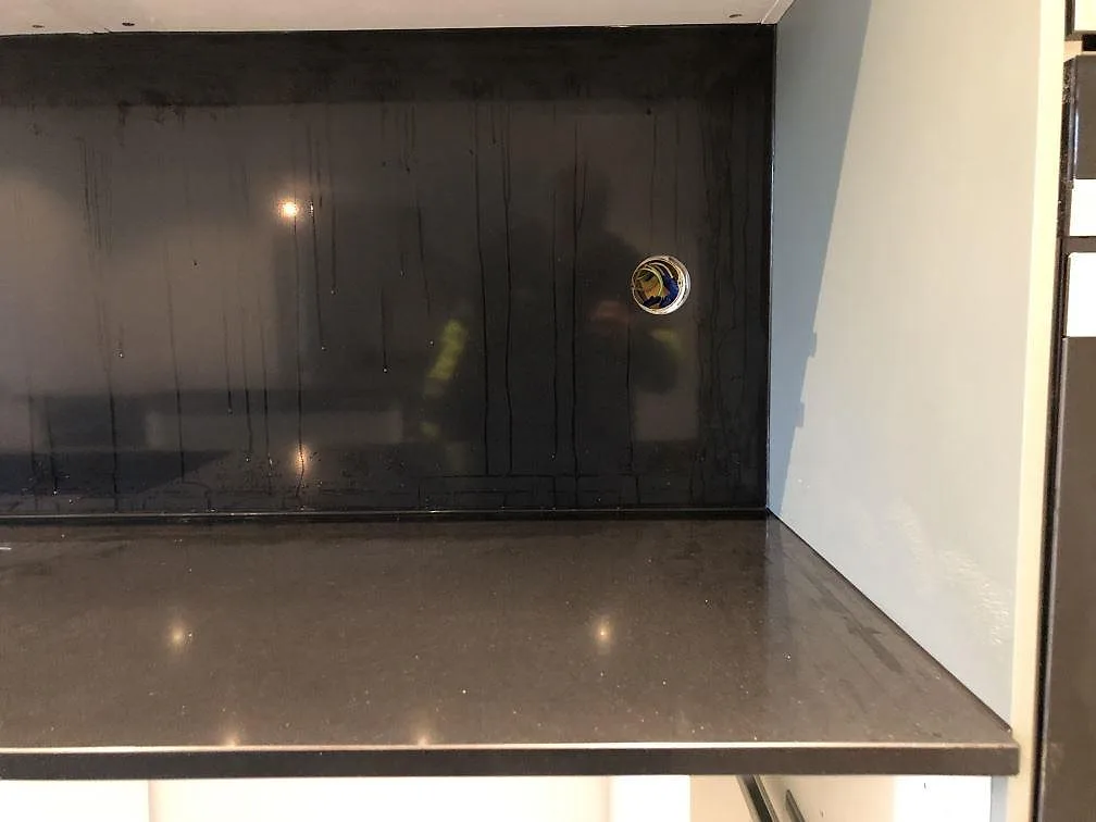 Köksbänkskiva i svart Silestone Negro Tebas med uppvikt stänkskydd i samma sten i ett kök under inredning i Svedala.