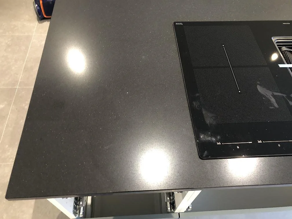 Närbild på induktionshällen övermonterad i den svarta Silestone Negro Tebas-skivan på köksön i Svedala.