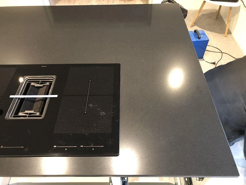Svart Silestone Negro Tebas köksö med integrerad induktionshäll och fläkt sedd uppifrån i ett kök i Svedala.
