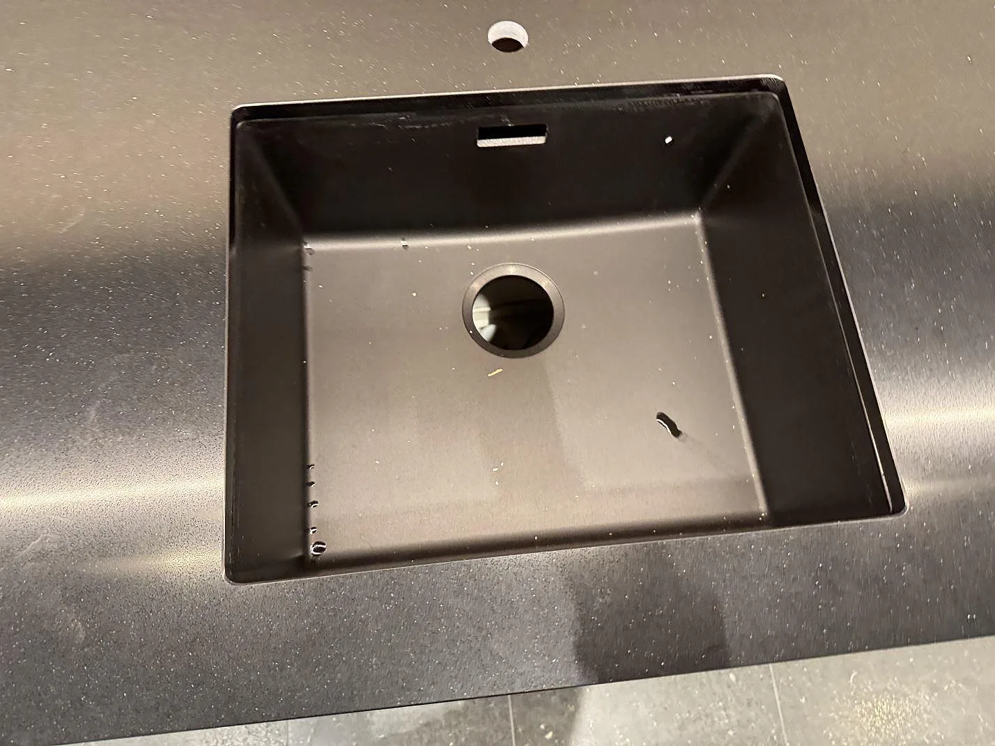 Närbild på svart diskho i bänkskiva av polerad Silestone Night Tebas komposit i Mölndal.