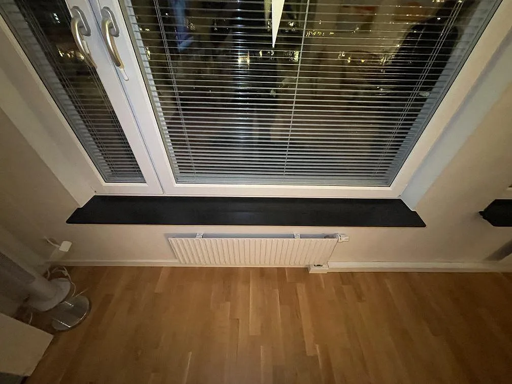 Lång fönsterbänk i Silestone Night Tebas kvartskomposit, matt svart yta över radiator i ett rum i Stockholm.