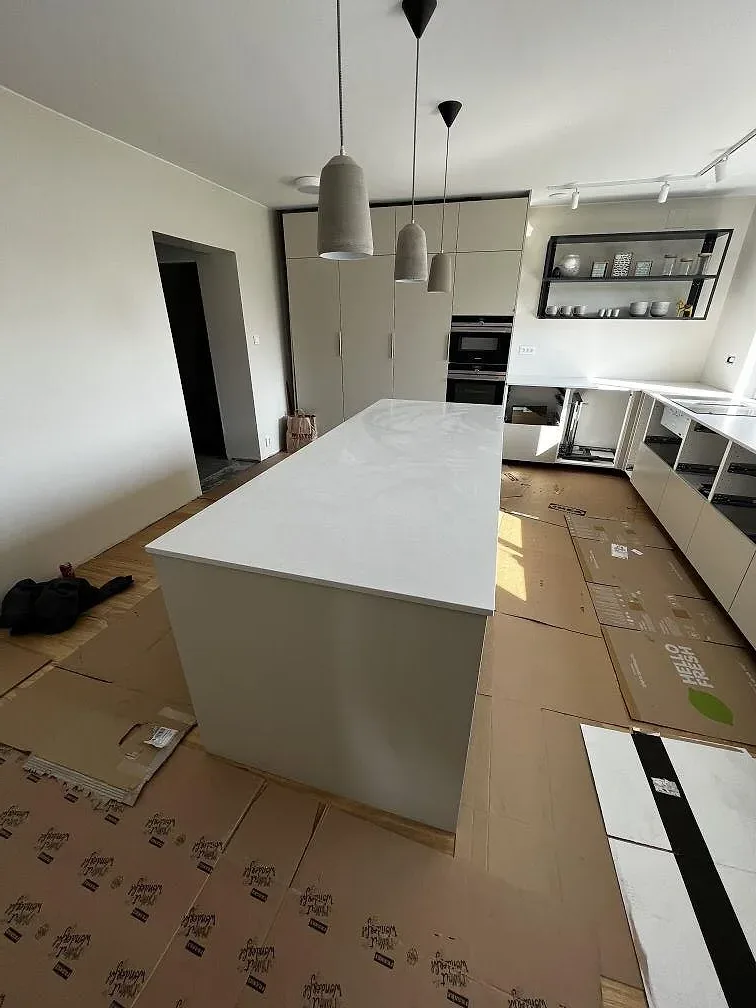 Köksö och bänkskiva i greige Silestone Nolita med matt yta och pendelarmaturer i ett kök under montering i Eslöv.
