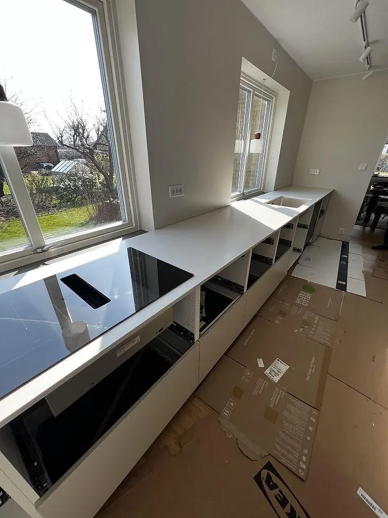 Köksbänkskiva i Silestone Nolita med induktionshäll och fönster mot trädgården i ett kök i Eslöv.