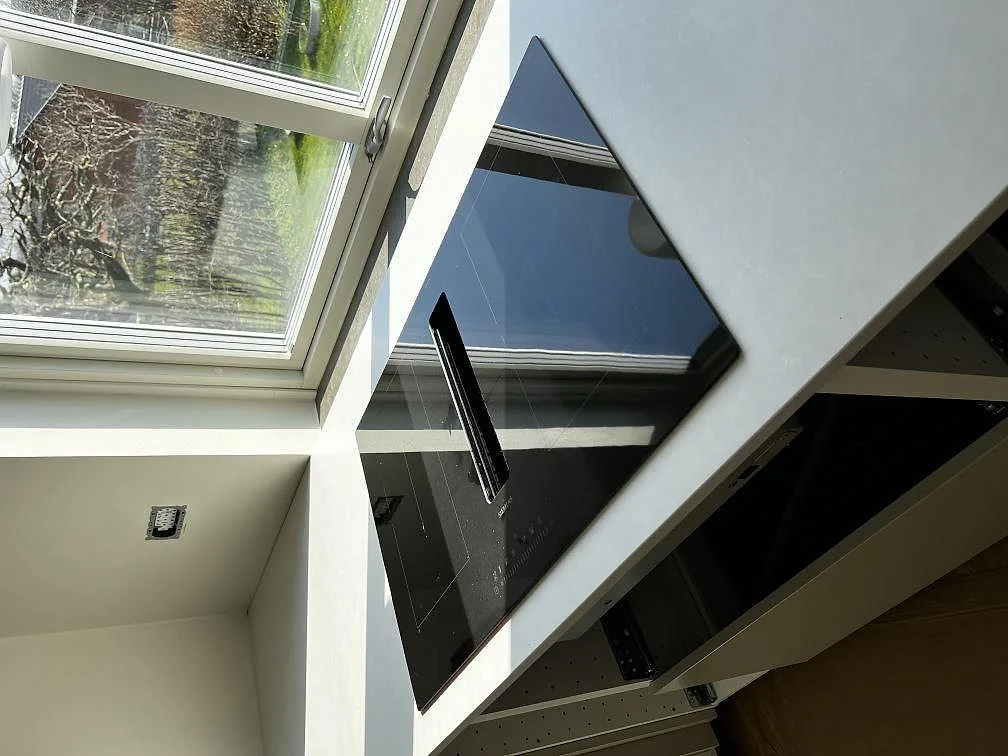 Köksbänkskiva i Silestone Nolita, matt greige kvartskomposit, med infälld svart induktionshäll och takfönster i ett kök i Eslöv.