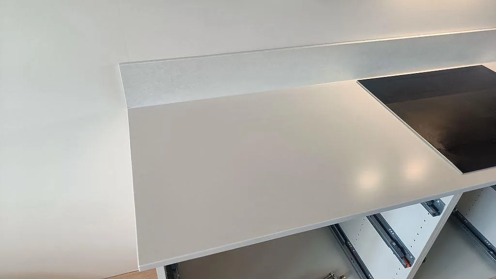 Närbild på ljus Silestone Nolita köksbänkskiva i Mocka med svart induktionshäll och låg stänkkant i Limhamn.