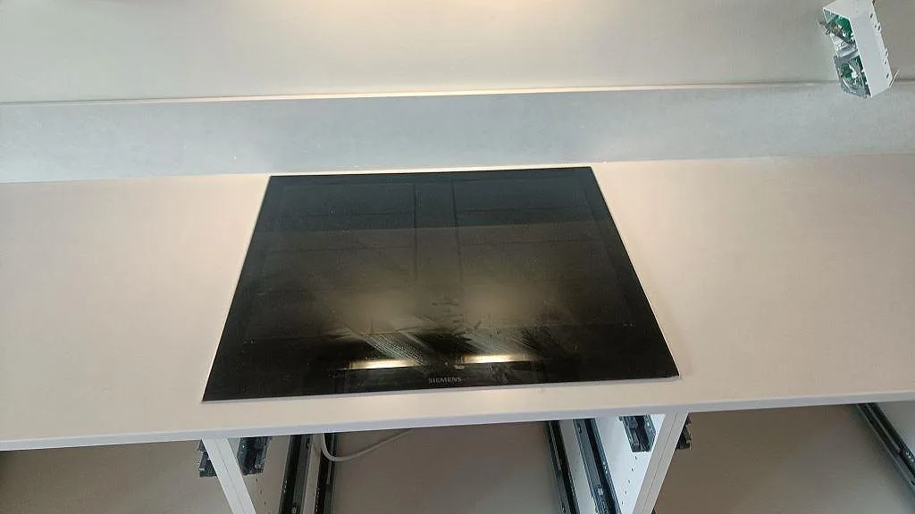 Svart induktionshäll infälld i en ljus Silestone Nolita bänkskiva med matt yta och 12 mm stänkkant i Limhamn.