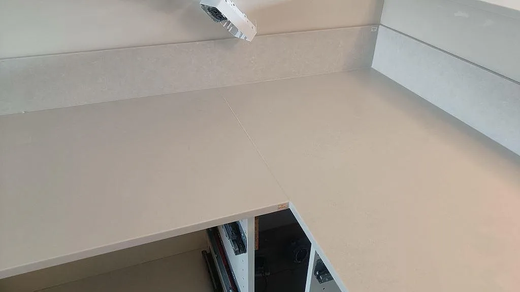 Hörndel av köksbänkskiva i Silestone Nolita, Mocka, med låg stänkkant och vita köksstommar i Limhamn.