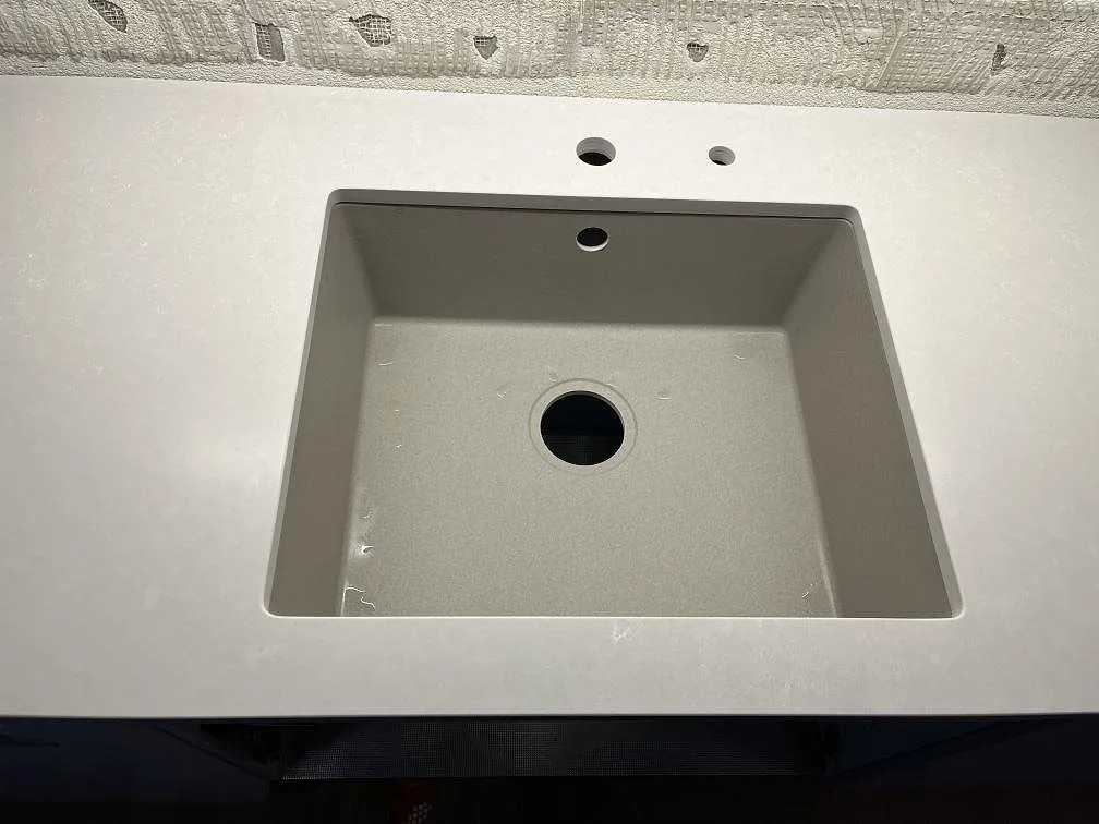 Närbild på underlimmad sandgrå kompositdiskho i en matt Silestone Nolita köksbänkskiva med borrade kranhål i Malmö.
