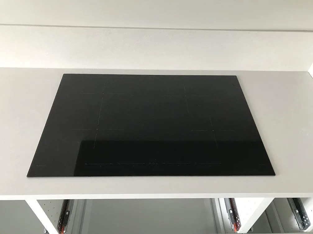 Infälld svart induktionshäll i en matt köksbänkskiva av Silestone Nolita i ett kök i Malmö.