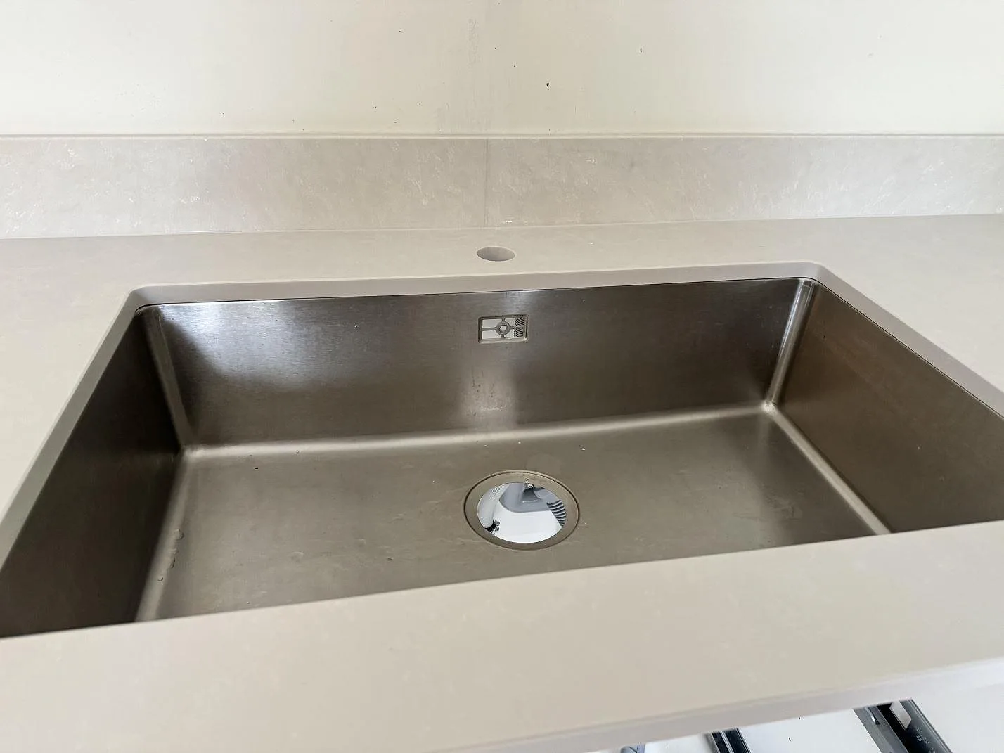Detalj av diskho i köksbänkskiva av vit Silestone Nolita med matt Mocka-yta och stänkskydd i Nättraby.