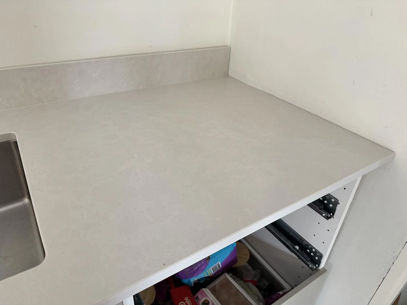 Hörnparti av köksbänkskiva i Silestone Nolita, matt vit komposit, med låg stänkkant i Nättraby.