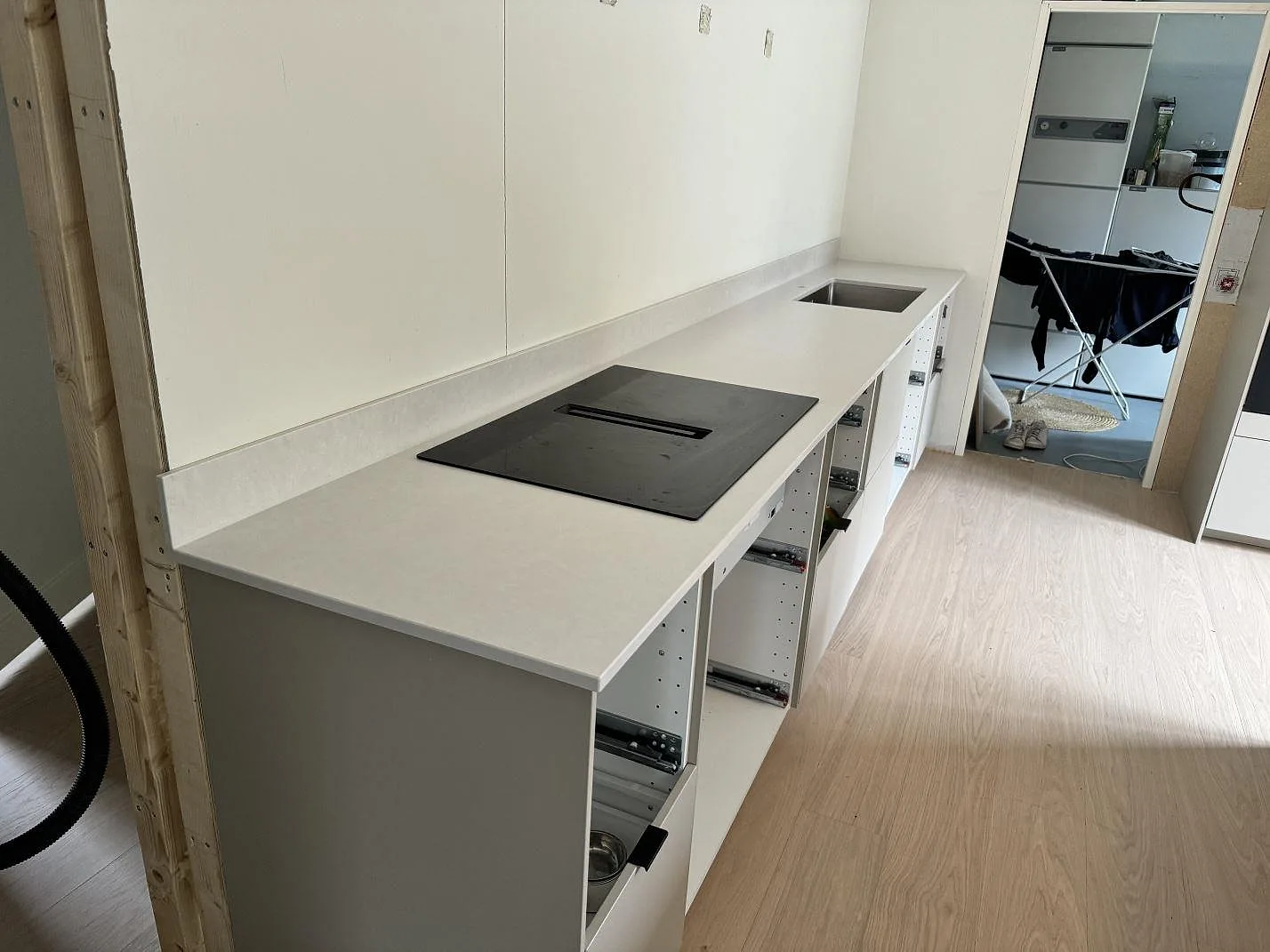 Lång köksbänkskiva i Silestone Nolita med matt vit komposit, stänkskydd och synliga köksstommar i Nättraby.