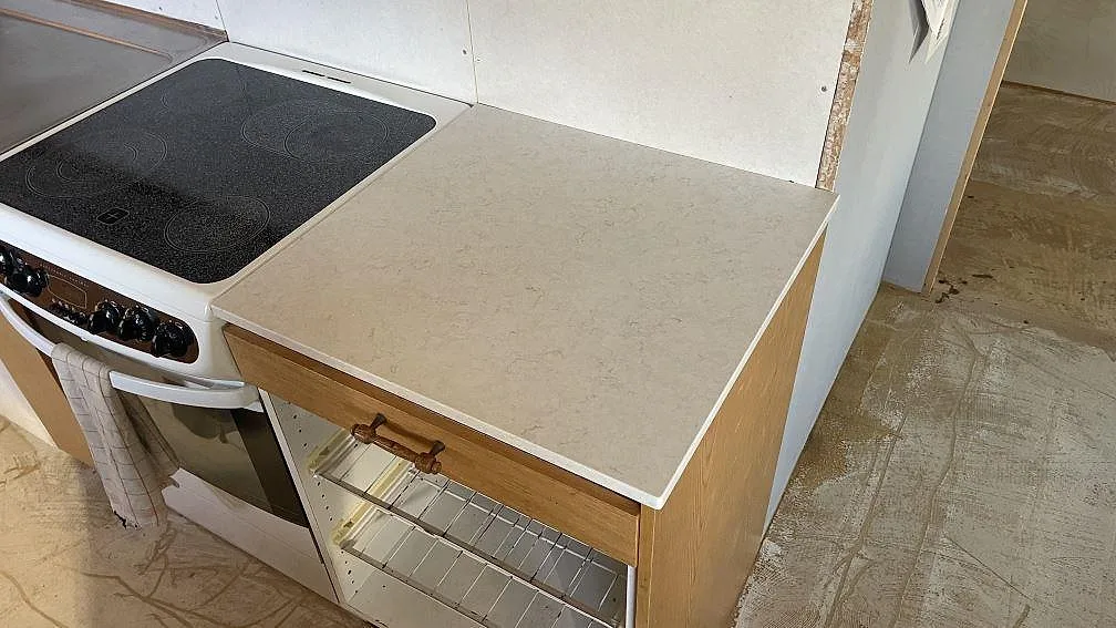 Närbild på polerad Silestone Pearl Jasmine som köksbänkskiva bredvid spisen, med subtil ådring i ett kök i Laholm under montering.