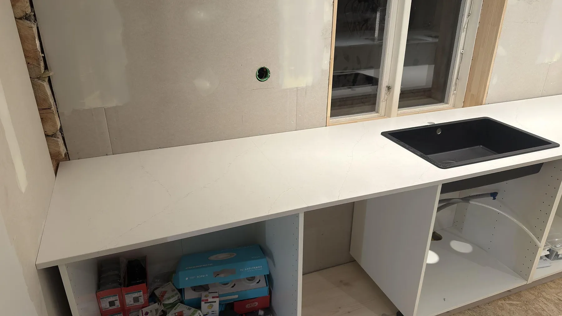 Matt vit Silestone Persian White köksbänk med underlimmad svart diskho och öppna köksstommar i ett kök i Falun.