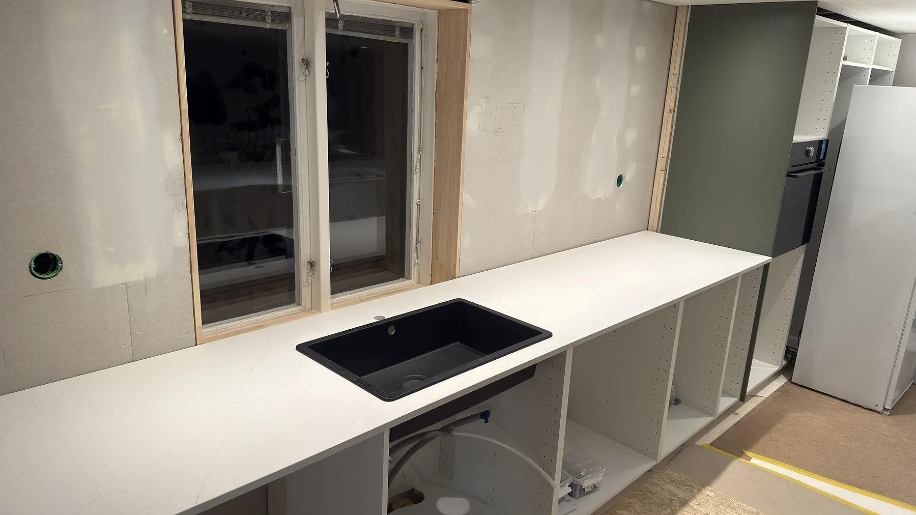 Köksbänk i Silestone Persian White, matt finish, med svart underlimmad diskho och fönster, fotograferad under montering i Falun.