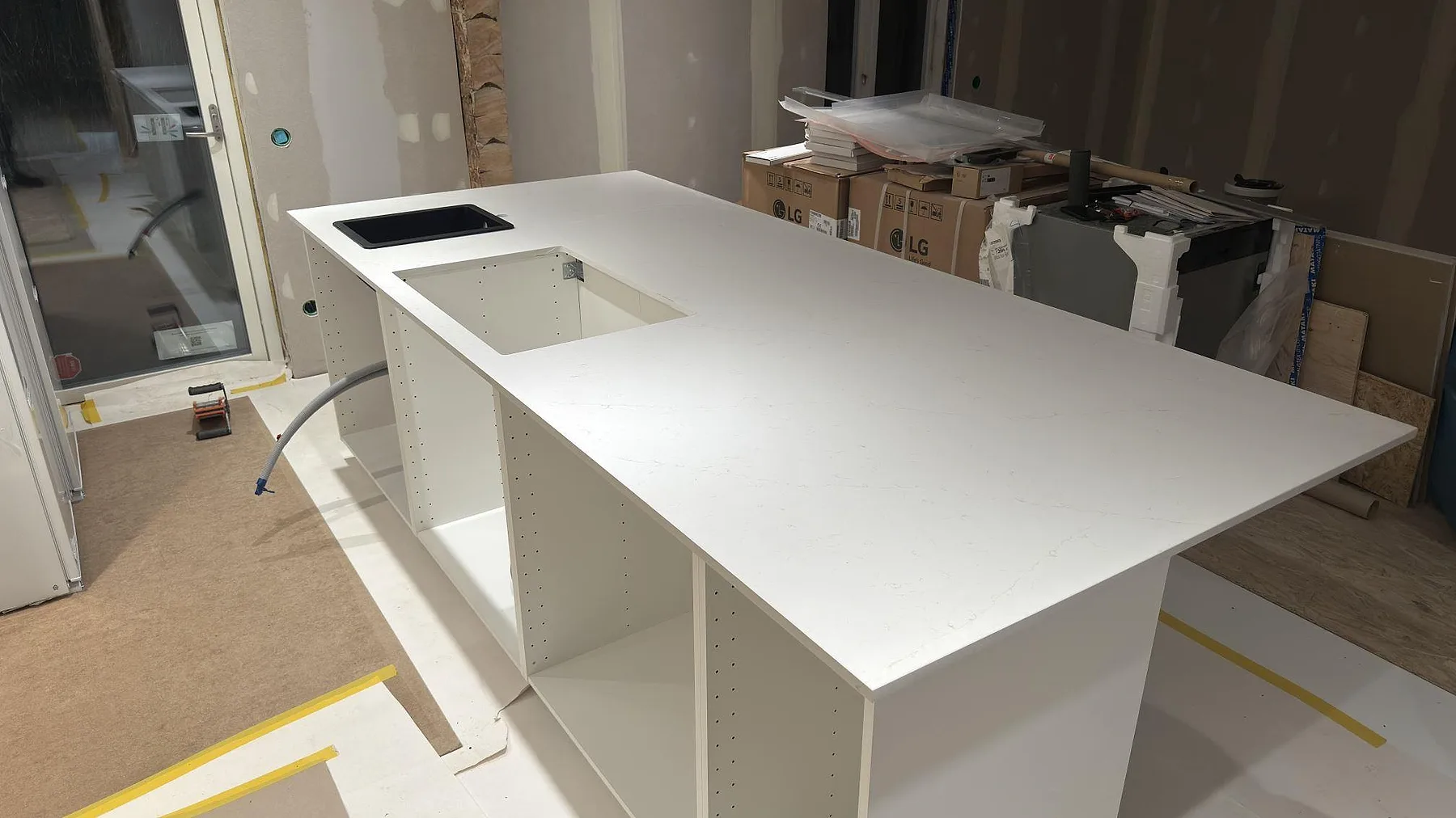 Köksö i vit Silestone Persian White, matt 20 mm, med förberedda urtag i ett kök under installation i Falun.