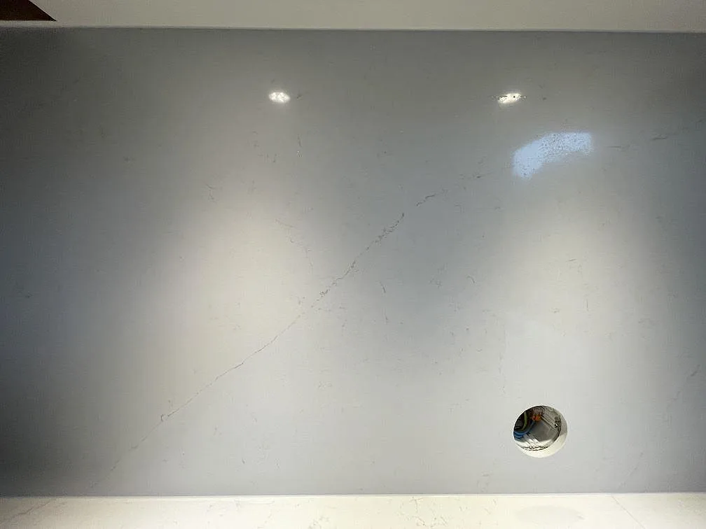 Närbild på den polerade ytan i Silestone Persian White med fina grå ådror på en köksbänkskiva i Falun.