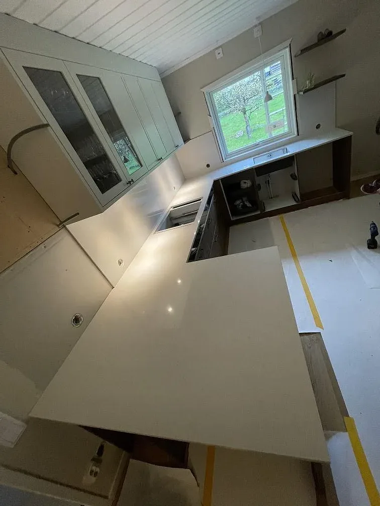 Köksbänkskiva i vit Silestone Persian White, polerad, med matchande stänkskydd i ett kök under montering i Falun.