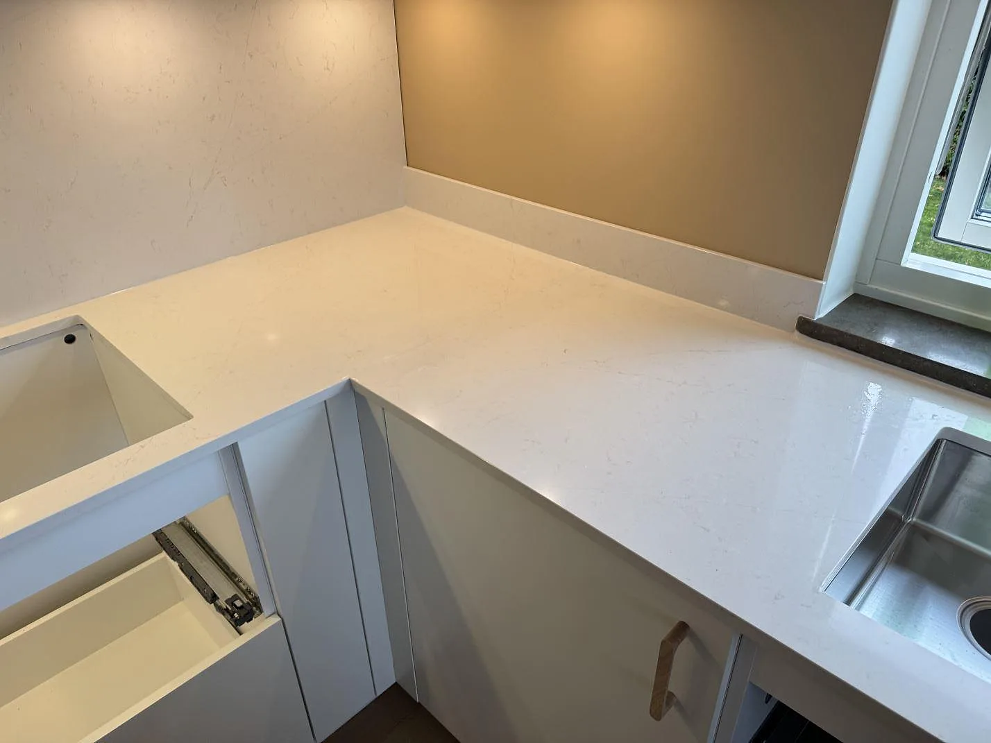 L-formad köksbänkskiva i vit Silestone Persian White med plats för underlimmad diskho i ett kök i Jönköping.