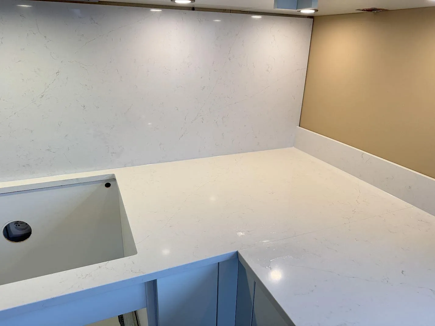 Köksbänkskiva och heltäckande stänkskydd i vit Silestone Persian White med mjuk grå ådring i ett kök i Jönköping.