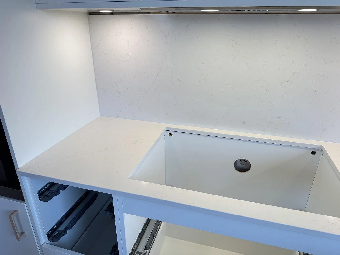 Polerad köksbänkskiva i vit Silestone Persian White under köksfläkten med matchande stänkskydd i samma sten i ett kök i Jönköping.
