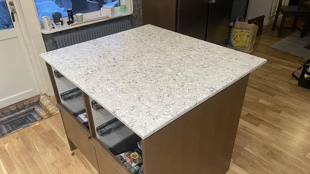 Polerad Silestone Pietra som köksö med gråvit spräcklighet, fotograferad från fönstersidan i Hällingsjö.