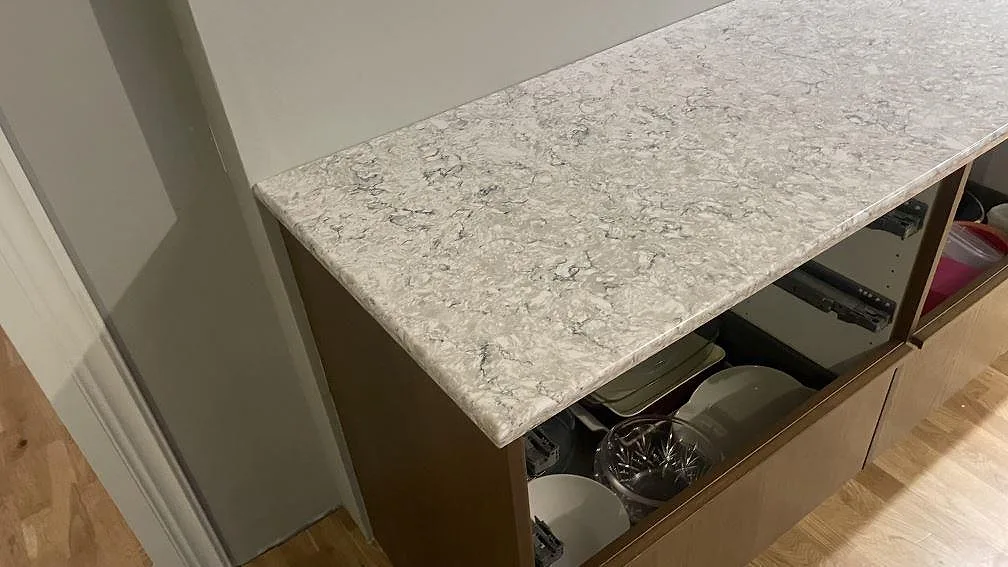 Detalj av väggbänk i polerad Silestone Pietra kvartskomposit över öppna köksstommar i Hällingsjö.