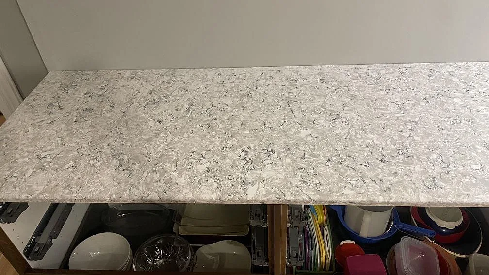 Lång köksbänkskiva i polerad Silestone Pietra med gråvit spräcklighet längs väggen i Hällingsjö.