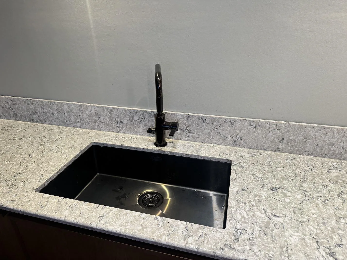 Svart underlimmad diskho med svart blandare i polerad Silestone Pietra köksbänkskiva i Hällingsjö.