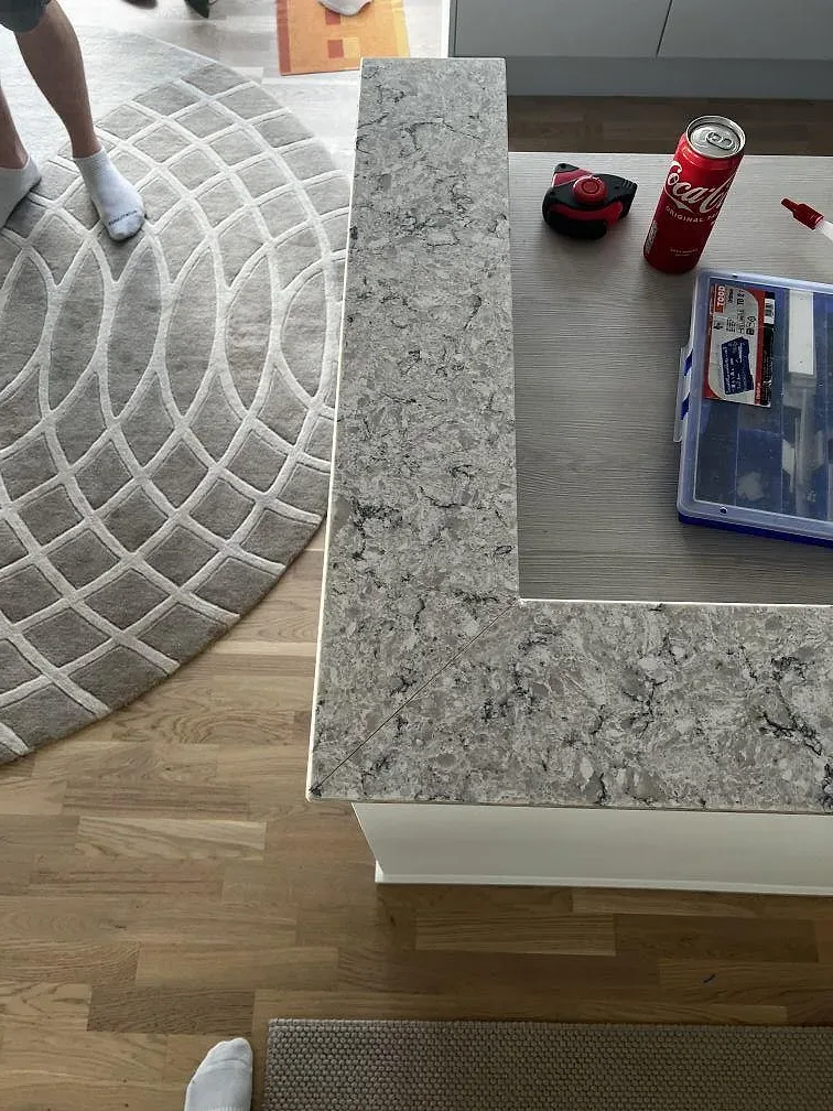 Detalj av gerad hörnskarv i polerad Silestone Pietra komposit på köksö med verktyg under montering i Malmö.