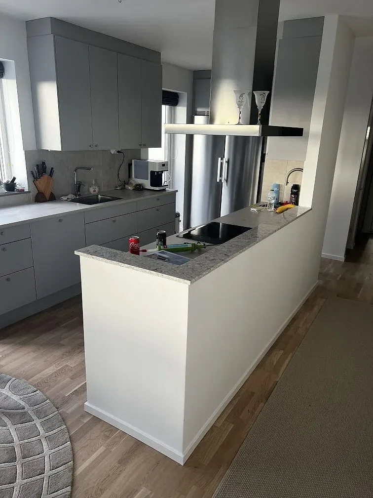 Köksö med bänkskiva i polerad Silestone Pietra, gråvit kvartskomposit med svart induktionshäll i ett kök i Malmö.