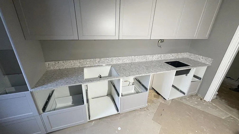 Köksbänkskiva i grå Silestone Pietra, polerad kvartskomposit, med stänkkant, svart diskho och hällöppning i ett kök i Malmö.