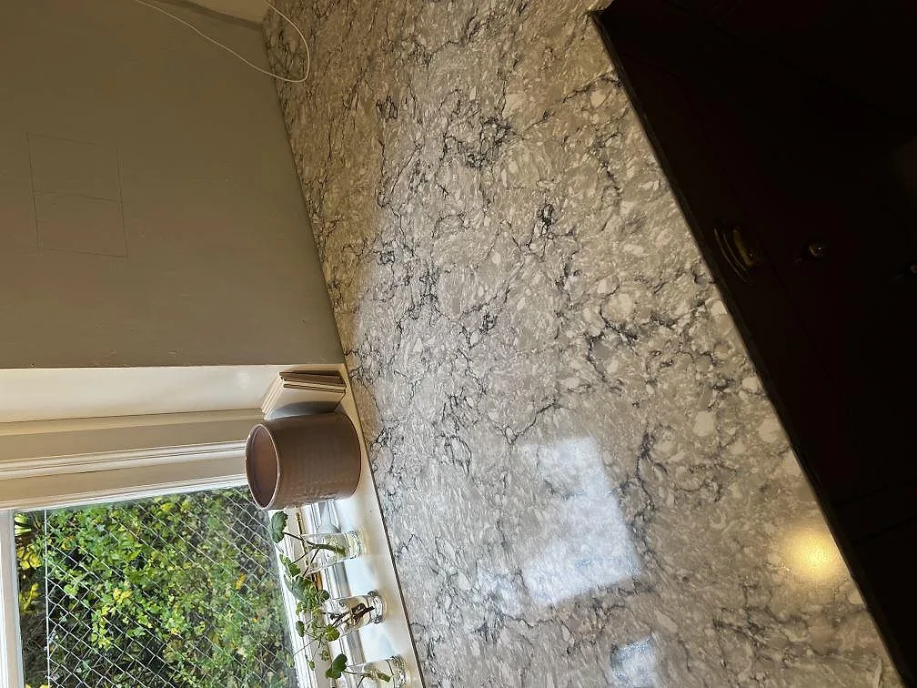 Närbild på den polerade grå kvartskompositen Silestone Pietra i en köksbänkskiva vid fönstret i Tygelsjö.
