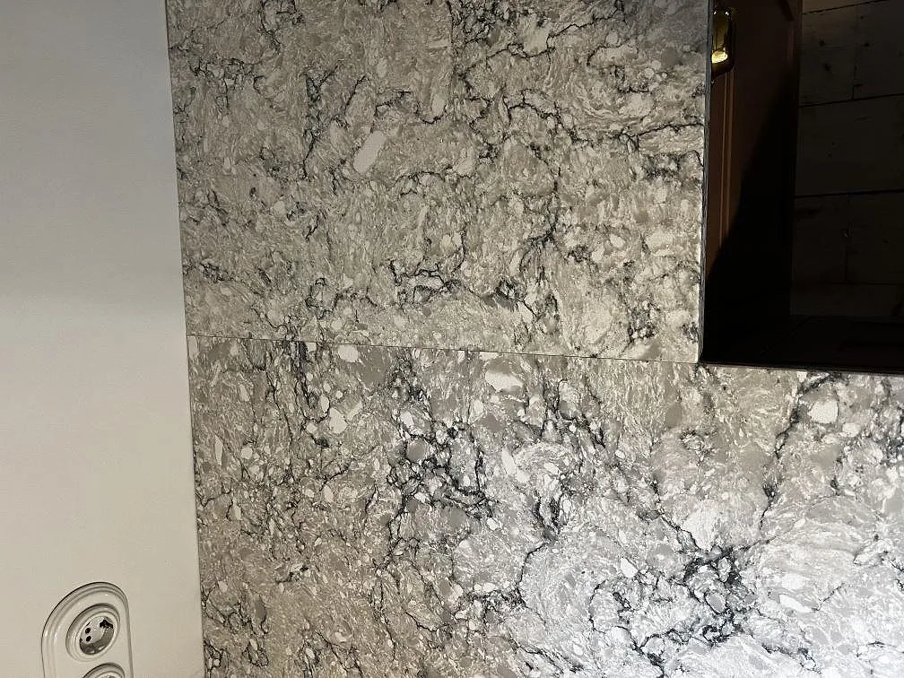 Detalj av polerad Silestone Pietra med häll och låg stänkkant i samma sten i köket i Tygelsjö.