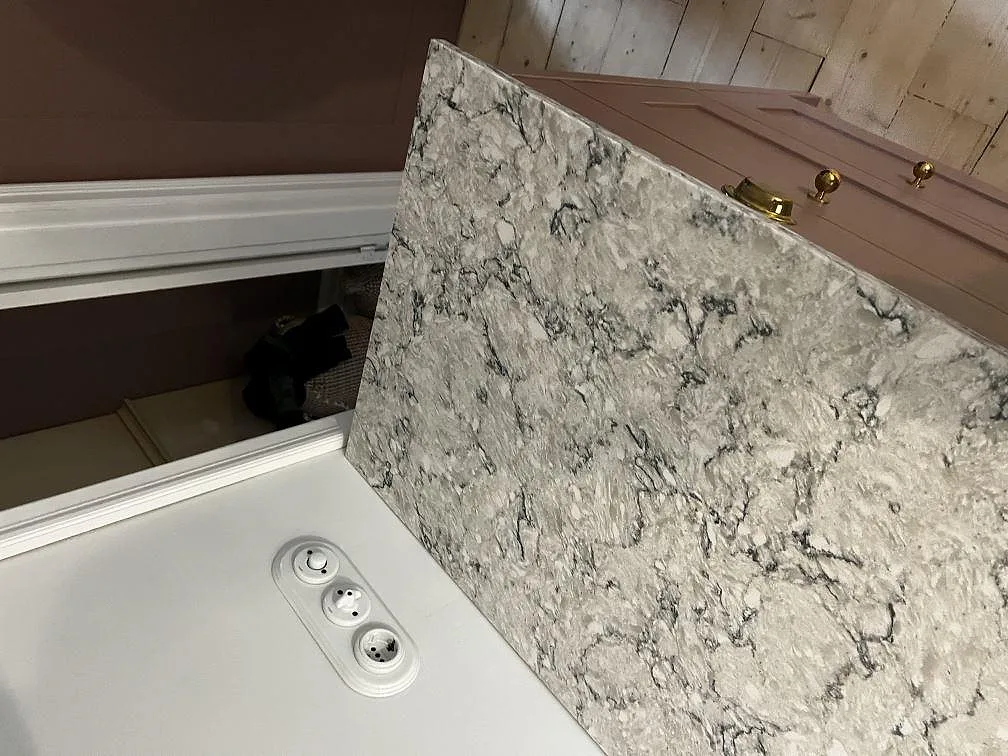Uppvikt stänkkant i polerad Silestone Pietra bakom köksbänkskivan i ett kök med träinredning i Tygelsjö.
