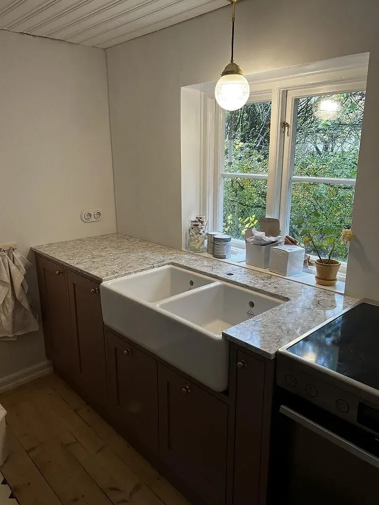 Köksbänkskiva i polerad Silestone Pietra, grå kvartskomposit, med vit underlimmad diskho och häll i ett kök i Tygelsjö.