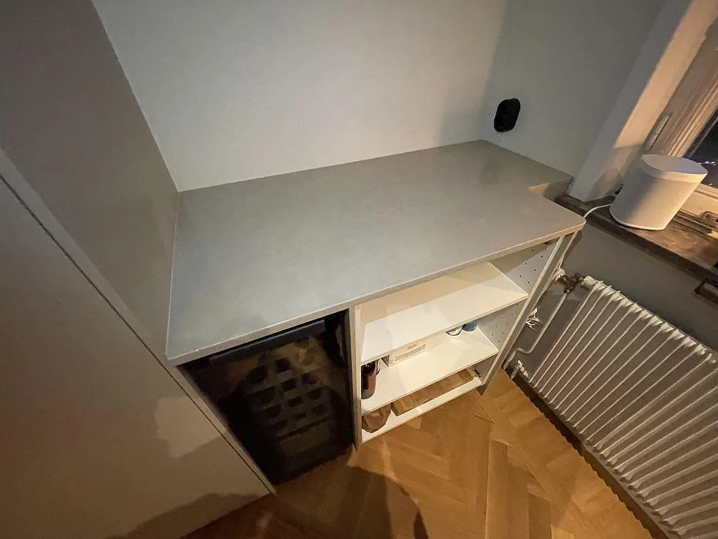 Köksbänkskiva i ljusgrå, betongliknande Silestone Poblenou i matt Mocka-finish, 20 mm, monterad över en köksbänk med vinkyl under monteringen i ett kök i Bromma.