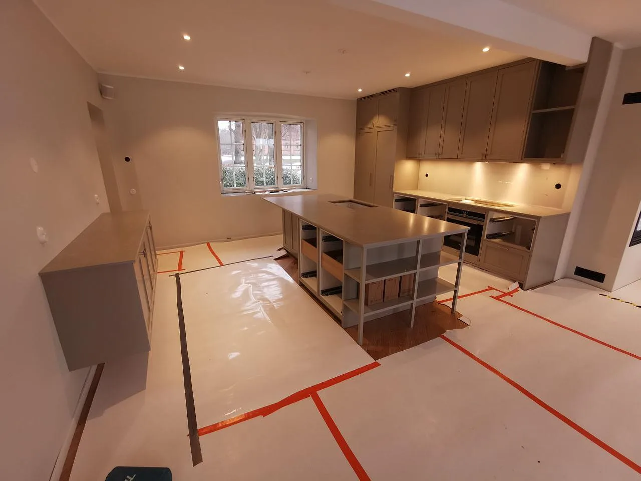 Köksbänkskiva och köksö i Silestone Poblenou Mocka, matt beige komposit, i ett stort kök i Ystad fotograferat under montering.