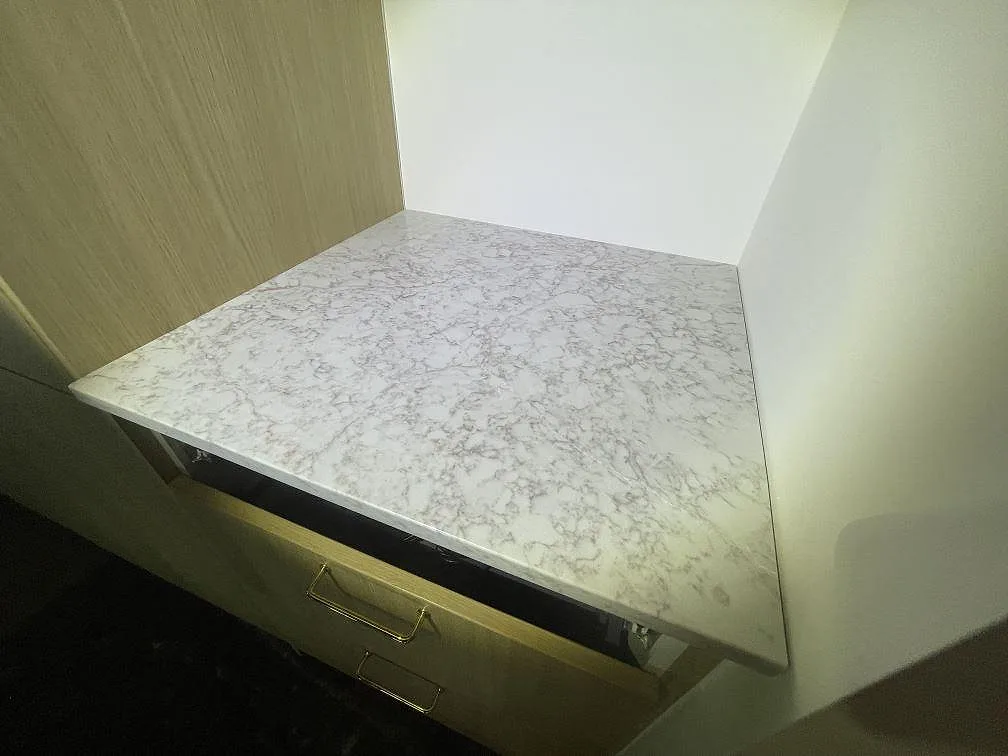Köksbänkskiva i Silestone Riviere Rose ovanifrån, ljus gråbeige kvartskomposit med fin grå ådring och nedvikt stengavel, i ett kök i Vaxholm.