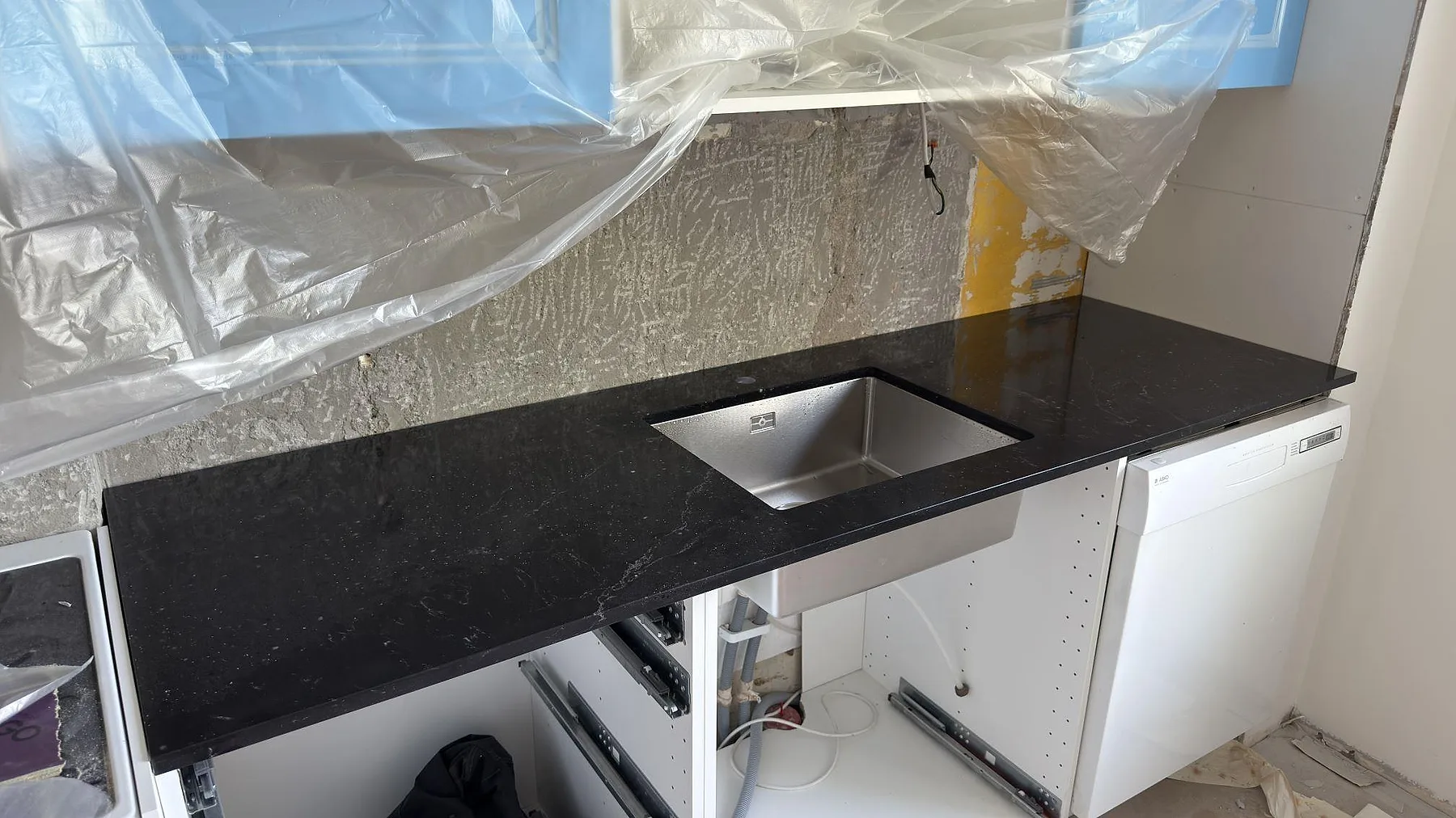 Köksbänkskiva i Silestone Romantic Ash, polerad kvartskomposit, med synlig rostfri diskho under montering i Uppsala.