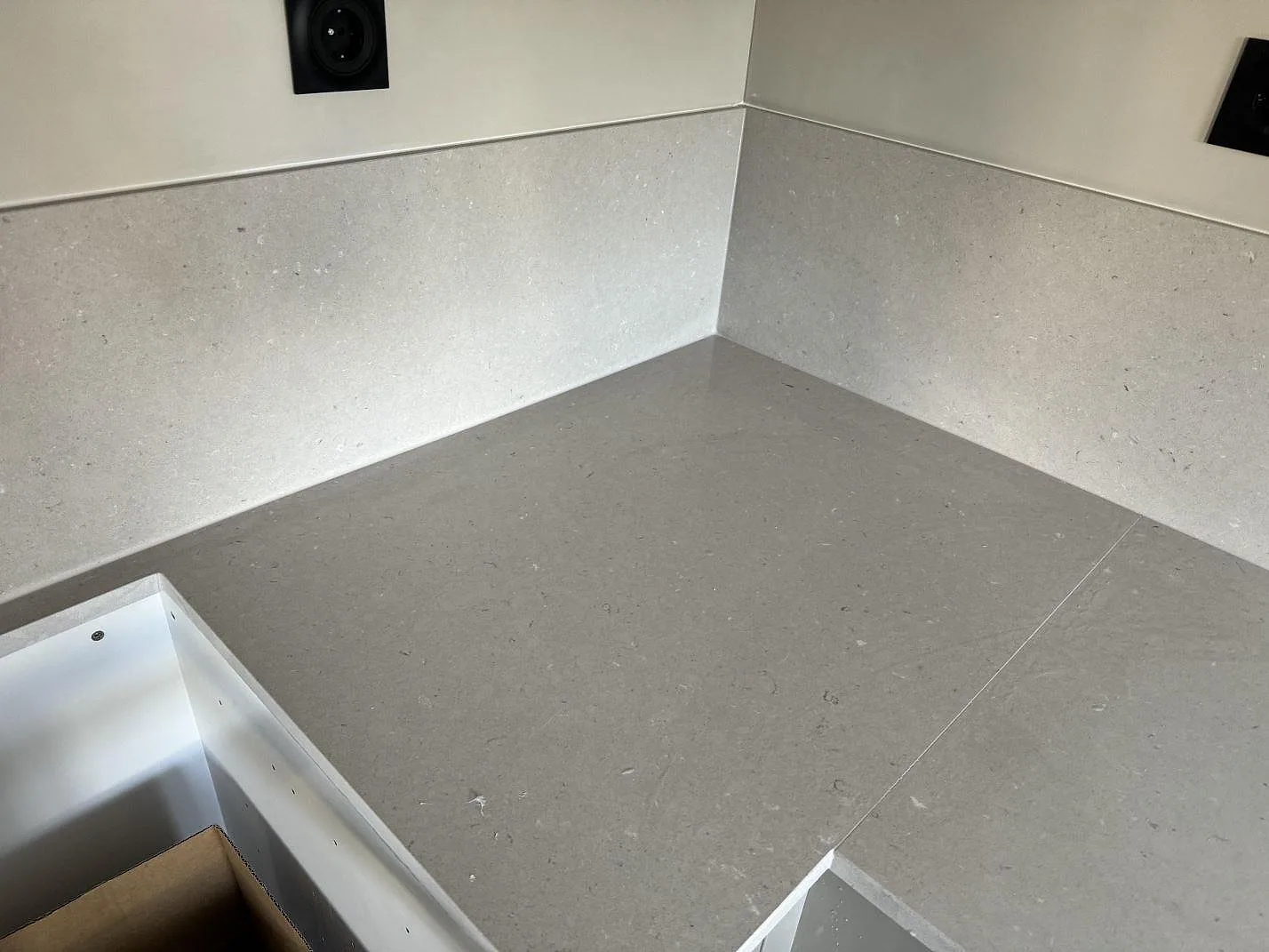Köksbänkskiva i grå Silestone Royal Reef, matt Mocka-finish, med matchande stänkskydd i ett kök i Åhus.