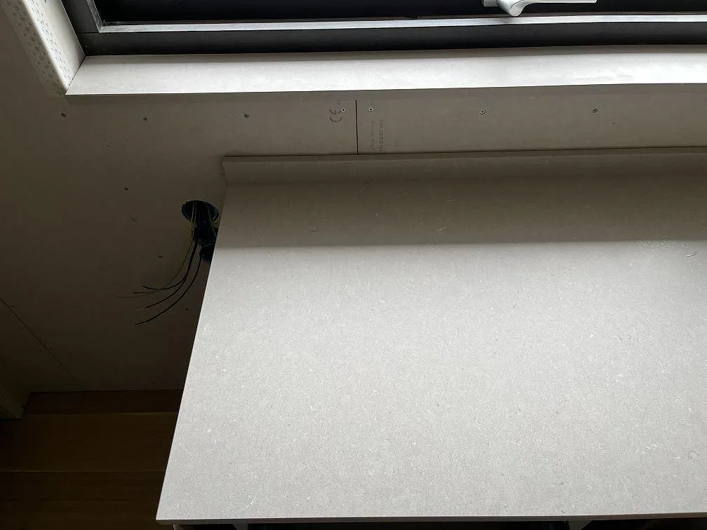 Installerad köksbänkskiva i matt Silestone Royal Reef vid fönster, med synlig framdragen el under montering i ett kök i Ängelholm.