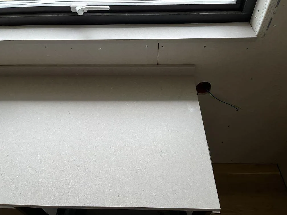 Matt Silestone Royal Reef köksbänkskiva längs fönstervägg med fönsterbänk i samma kvartskomposit, fotad under montering i ett kök i Ängelholm.