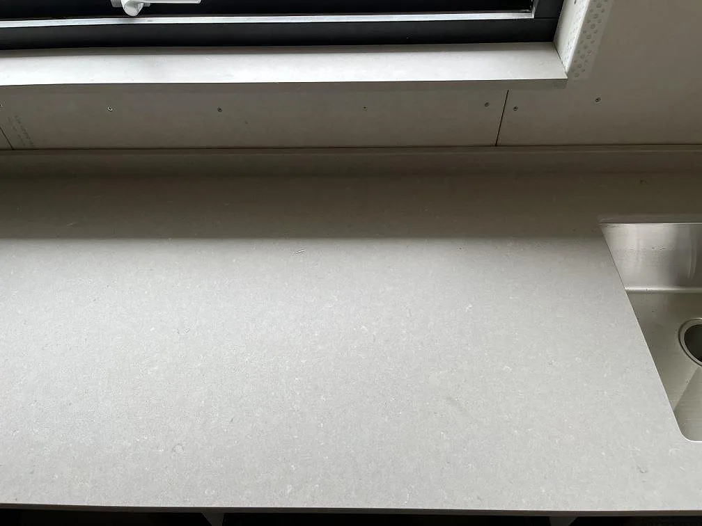 Ljus krämbeige köksbänkskiva i Silestone Royal Reef med underlimmad rostfri diskho och matchande fönsterbänk i ett kök i Ängelholm.