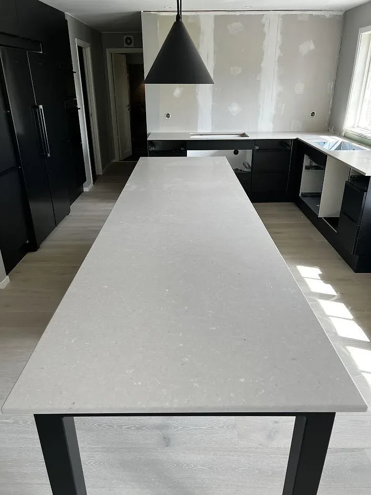 Närbild av lång köksbänkskiva i Silestone Royal Reef, Mocka, med ljus komposityta och svarta köksstommar i Ängelholm.