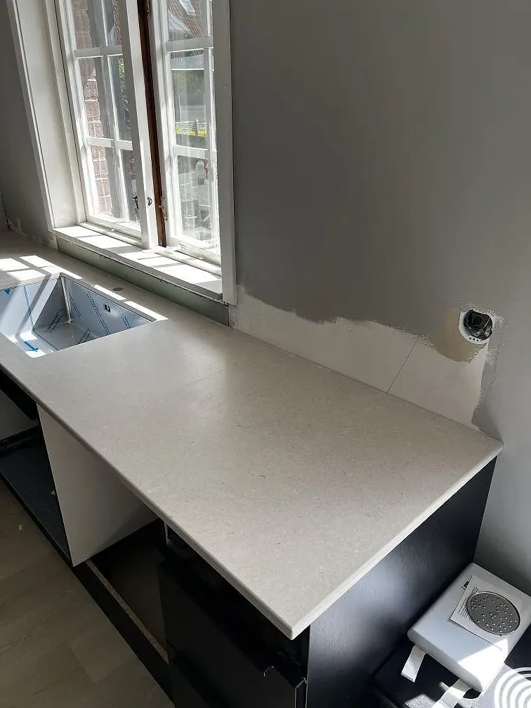 Hörn vid fönster med köksbänkskiva i Silestone Royal Reef, Mocka, monterad mot svart inredning i Ängelholm.
