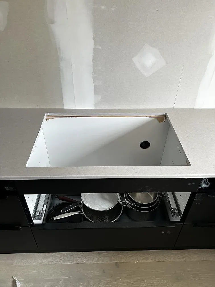 Öppning för häll i köksbänkskiva av Silestone Royal Reef, Mocka, ovanför svarta köksstommar i Ängelholm.