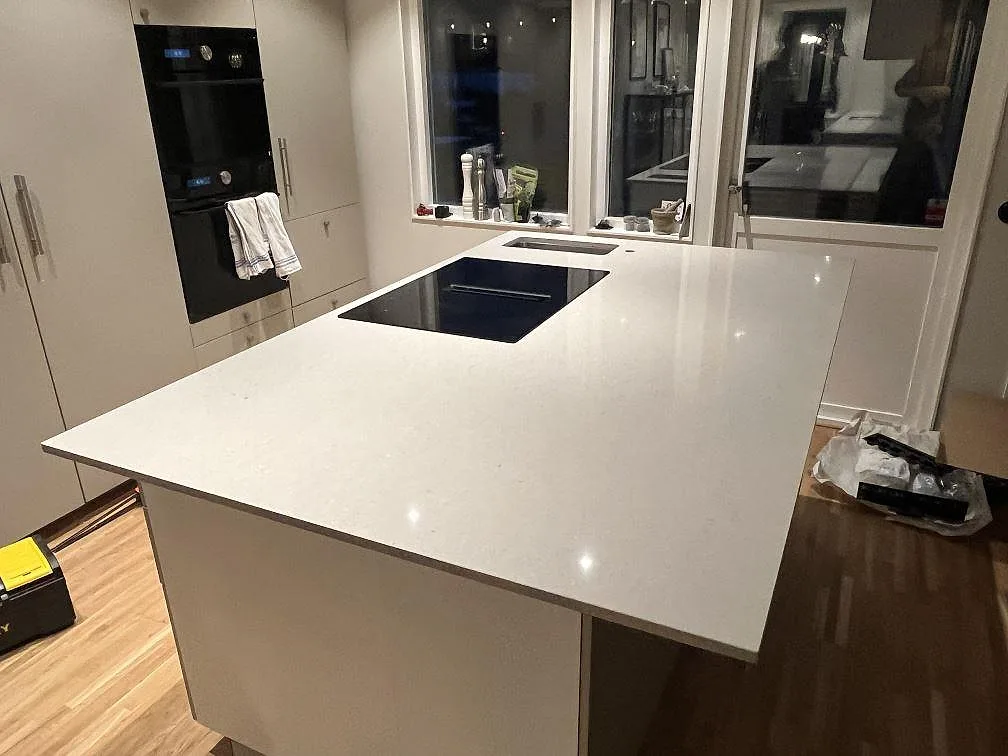 Köksö i ljus Silestone Royal Reef, polerad kompositsten med induktionshäll i ett kök i Bålsta.