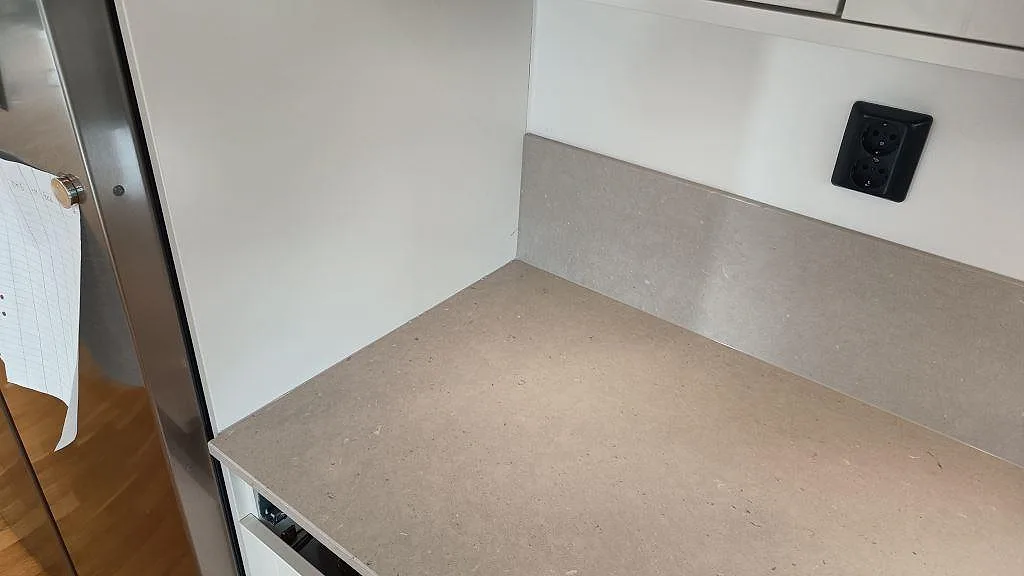 Närbild av polerad Silestone Royal Reef på köksbänk och stänkskydd, ljus kvartskomposit med små mineralinslag i Barsebäck.