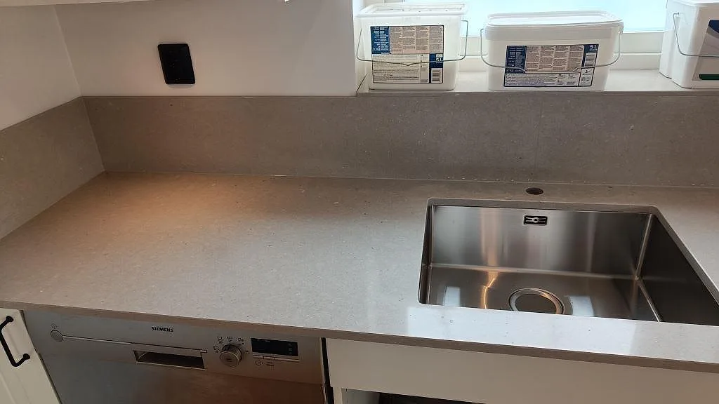 Lång arbetsyta i polerad Silestone Royal Reef, ljus kvartskomposit, med diskho och låg stänkkant i Barsebäck.